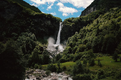 Scenic view of waterfall in forest against sky