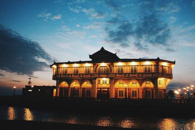 Building by lake against sky at dusk