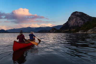 Woman on boat in lake against sky during sunset