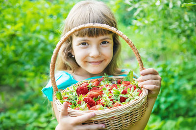 Smiling girl holding strawberries in basket