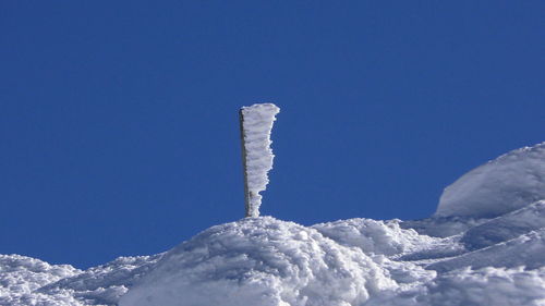 Low angle view of snow covered mountain against blue sky