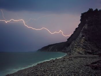 Scenic view of sea against sky at night with lightning 