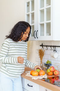 Side view of woman holding fruits at home
