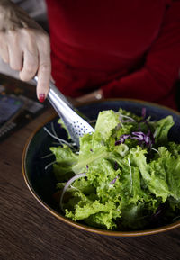 Cropped hand of woman mixing lettuce with salad dressing