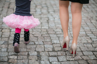 Low section of woman and girl walking on footpath