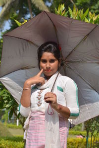 Young woman holding umbrella while standing outdoors