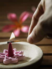 Cropped hand blowing candle on wooden table