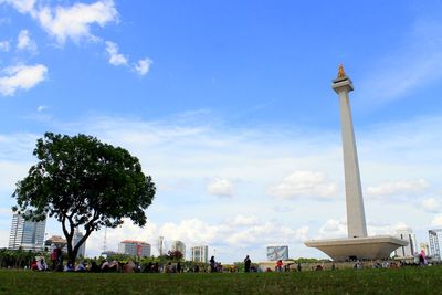 Group of people in front of built structure against blue sky