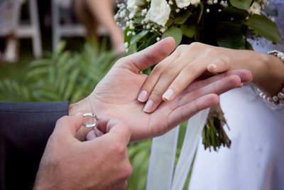 Cropped image of wedding couple holding hands for ring ceremony
