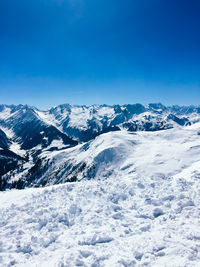 Scenic view of snowcapped mountains against blue sky