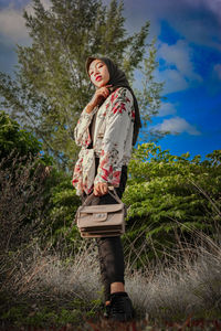 Low angle view of woman standing by tree against sky