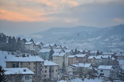 Aerial view of townscape by snowcapped mountain against sky