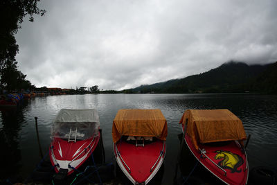 Panoramic view of boats moored in lake against sky