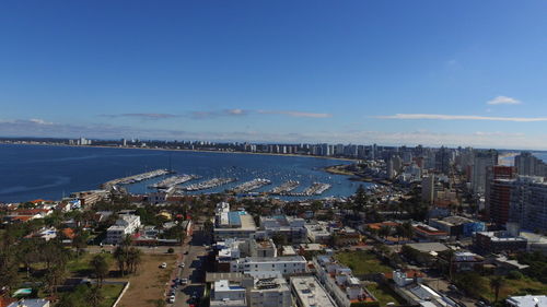 High angle view of buildings by sea against blue sky