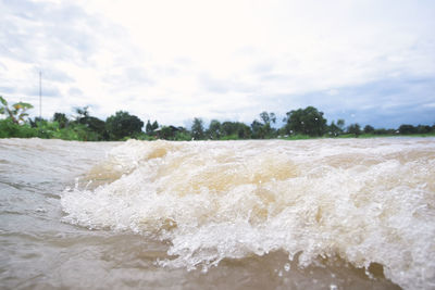 Waves splashing on shore against sky