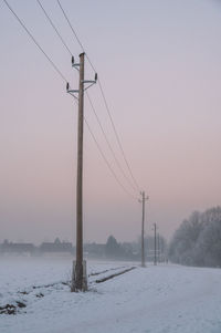 Snow covered field against sky during sunset