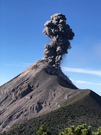 Low angle view of volcano against blue sky