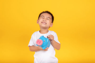 Happy boy standing against yellow background