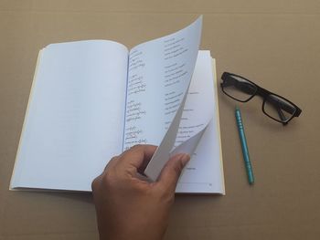 Cropped image of hand holding book on table