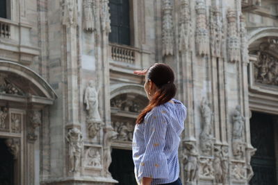 Rear view of woman standing against building in city