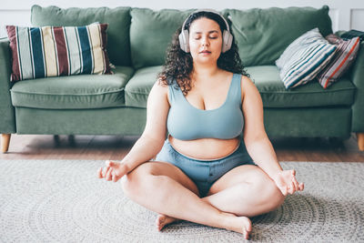 Curvy woman meditating at home