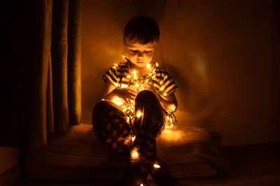 Full length of boy with illuminated lights at home