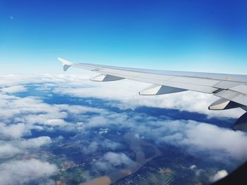 Aircraft wing over clouds seen though window