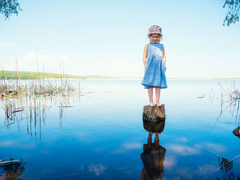 Boy standing by lake against sky