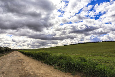 Road amidst field against sky