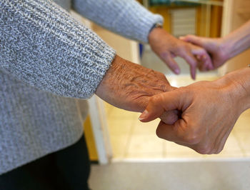 Man and woman holding hands while standing at home