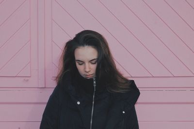 Portrait of beautiful young woman standing against wall