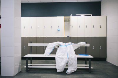 Protective wear and face shield kept on bench in locker room at hospital