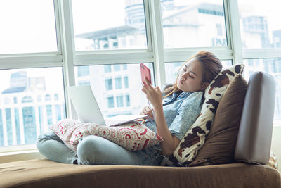 Woman using mobile phone while sitting at home