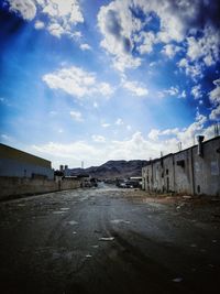 Empty road by buildings against sky in city