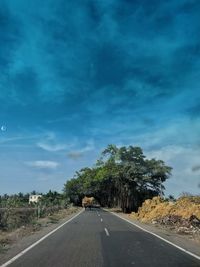 Road by trees against sky