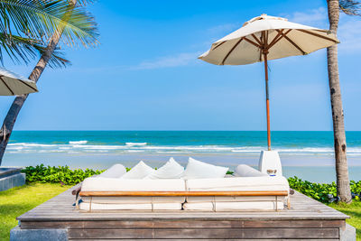 Lounge chairs by swimming pool at beach against sky