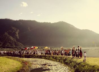 Group of people on field by mountains against sky