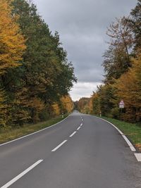 Road amidst trees against sky during autumn