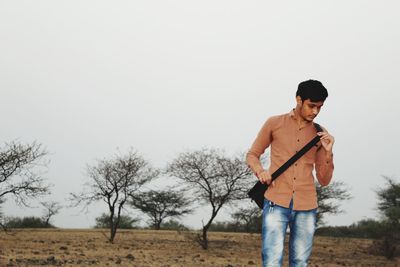 Young man standing on field against sky