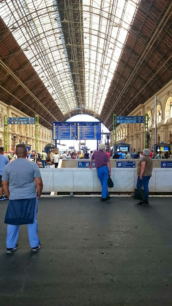 indoors, public transportation, men, lifestyles, transportation, railroad station, passenger, person, rail transportation, ceiling, travel, leisure activity, railroad station platform, full length, architecture, rear view, train - vehicle, standing