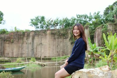 Side view portrait of young woman sitting by river