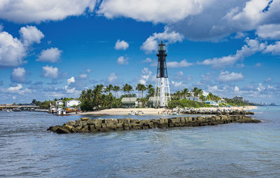 Lighthouse by sea against sky