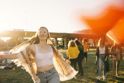 Smiling woman dancing with friends in background at event on sunny day