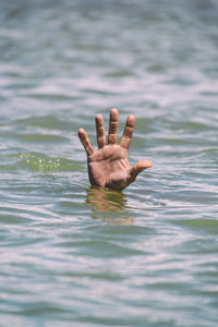 Cropped image of person drowning in sea