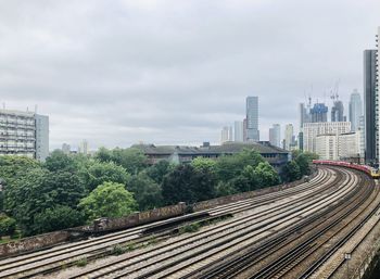 Railroad tracks by buildings in city against sky