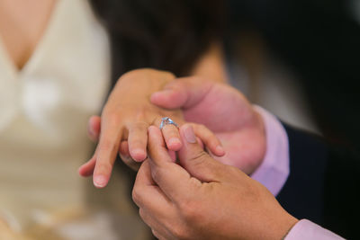 Close-up of bridegroom inserting wedding ring in bride finger