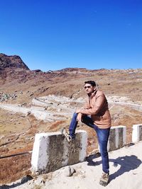 Full length of man standing on mountain against clear blue sky