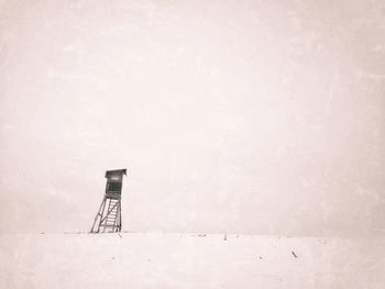 Lifeguard tower on snow covered land against sky