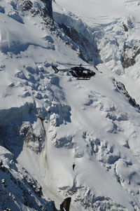 Scenic view of snowcapped mountains against sky with rescue helicopter