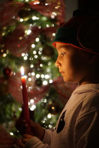 Close-up of boy holding candle in dark